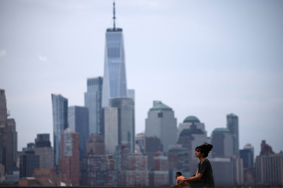 A woman enjoys the day in a park with the New York skyline in the background, in Hoboken, New Jersey, US, June 23, 2024.