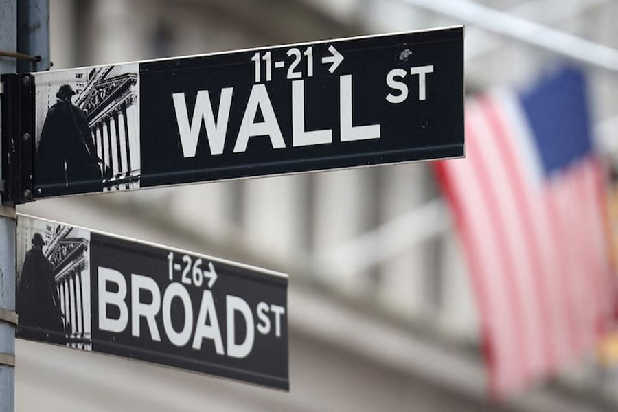 A Wall Street sign hangs in front of a US Flag outside the New York Stock Exchange (NYSE) before the Federal Reserve announcement in New York City, US, September 18, 2024.