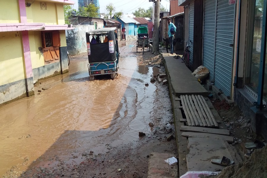 A three-wheeler striving to cross over the potholed Kuthipara-Thugnapara Road in Pabna town