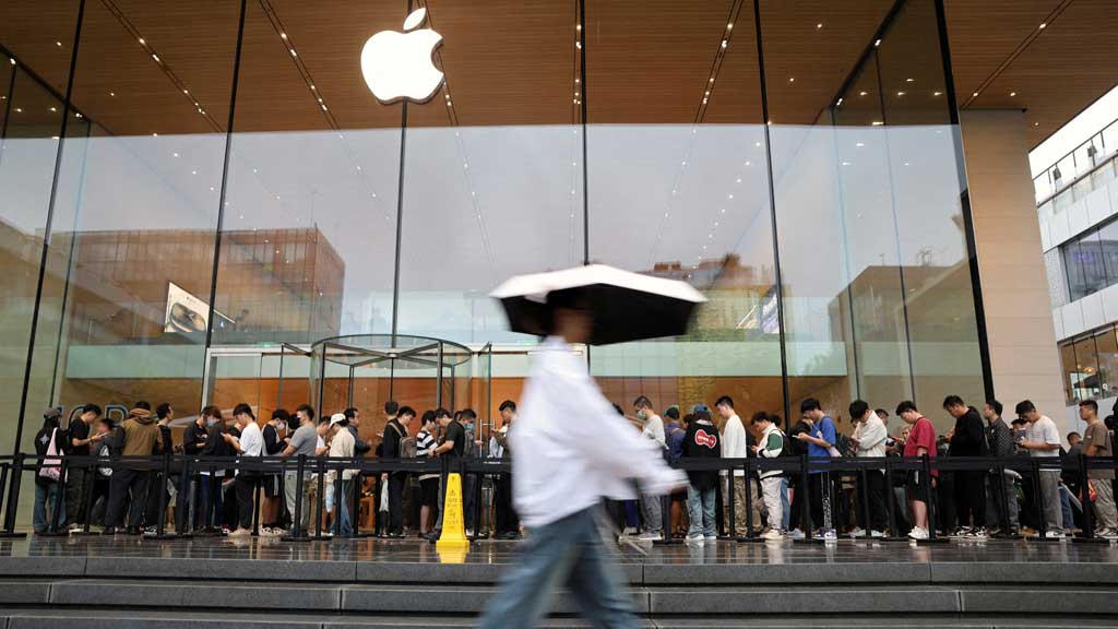 People line up outside an Apple store on a rainy day as the new iPhone 16 series smartphones go on sale, in Beijing, China, Sept. 20, 2024. REUTERS