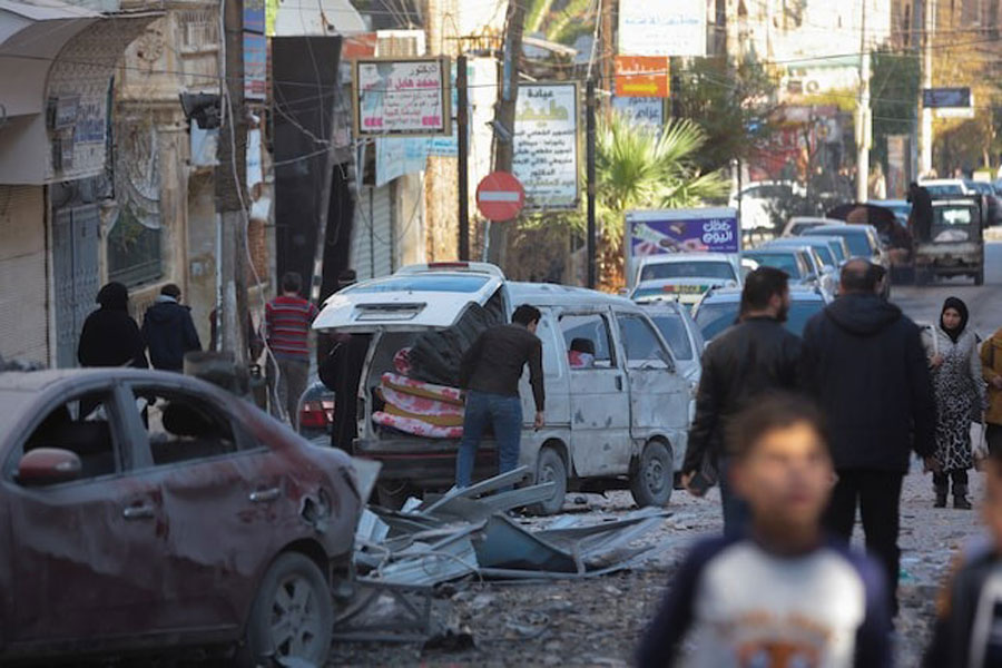 People walk past a damaged site in Aleppo, after the Syrian army said that dozens of its soldiers had been killed in a major attack by rebels who swept into the city, in Syria November 30, 2024.