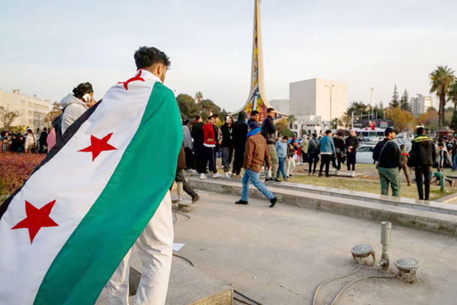 A man holds a revolutionary flag Tuesday as others celebrate during the third day of the takeover of Damascus, Syria, by insurgents