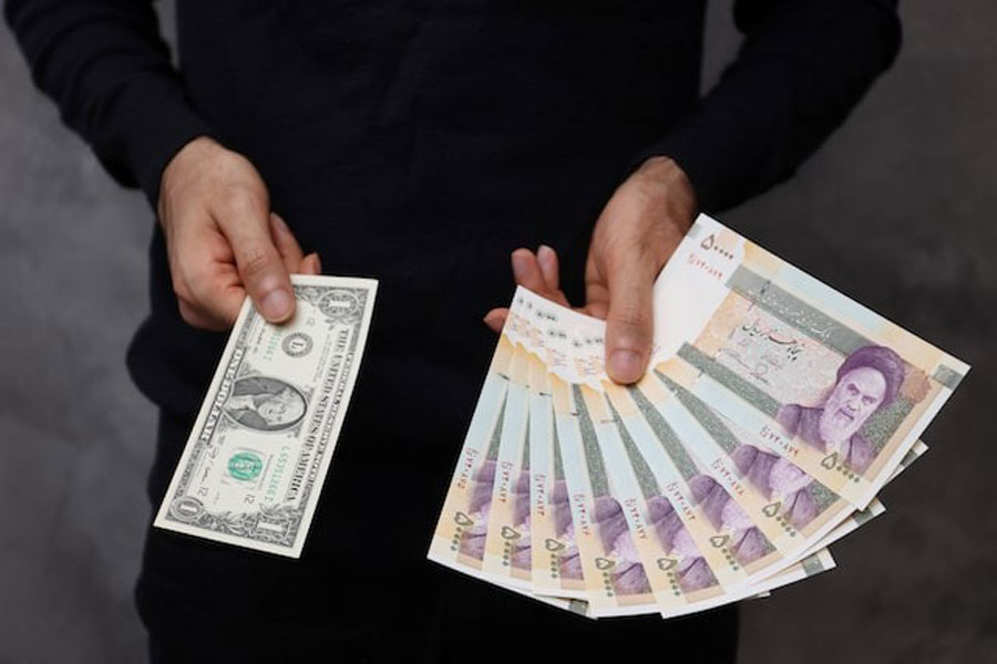 A currency dealer poses for a photo with a US one dollar bill and the amount being given when converting it into Iranian rials in an exchange shop in Tehran, Iran December 25, 2022.
