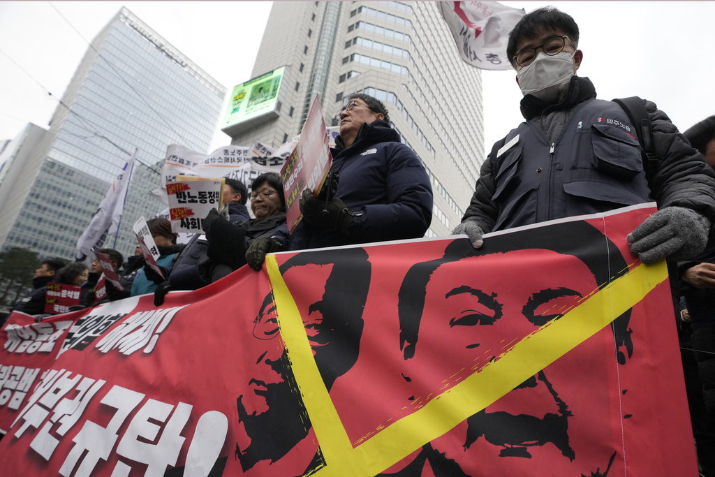 Protesters hold a banner showing images of impeached President Yoon Suk Yeol, right, and acting President Han Duck-soo during a rally demanding the arrest of Yoon in Seoul, South Korea, Saturday, Dec. 21, 2024. The banner reads "Denounce Han Duck-soo's veto." (AP Photo/Ahn Young-joon)