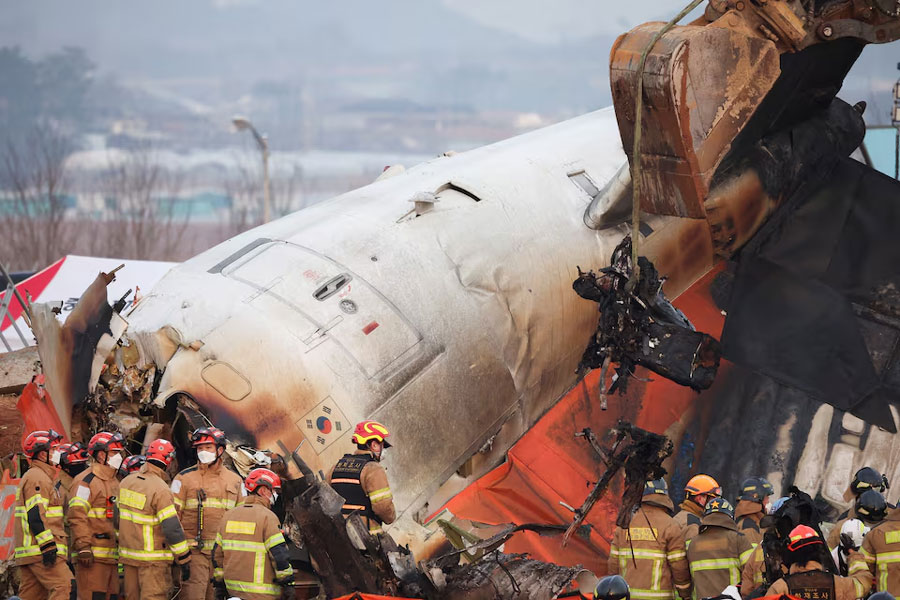 An excavator is used to lift burnt chairs from the wreckage of an aircraft that crashed after it went off the runway at Muan International Airport, in Muan, South Korea, December 29, 2024.