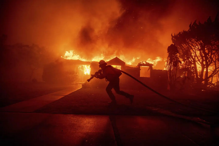 A firefighter battles the Palisades Fire as it burns a structure in the Pacific Palisades neighborhood of Los Angeles, January 8, 2024.