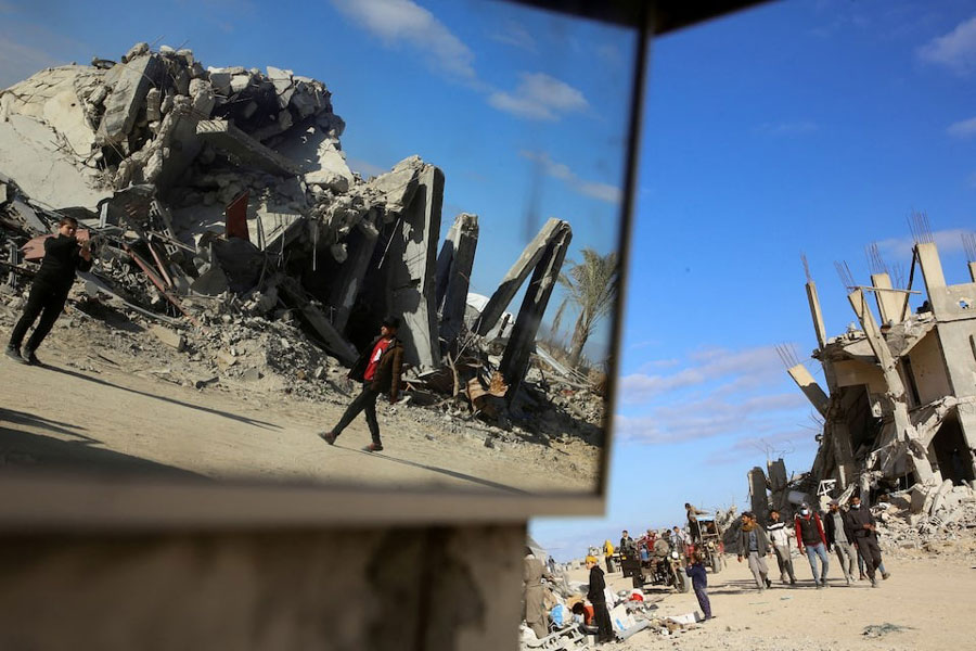 Palestinians walk past the rubble of houses and buildings destroyed during the war, following a ceasefire between Israel and Hamas, in Rafah in the southern Gaza Strip, January 20, 2025.