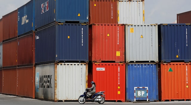 A woman rides a motorcycle as she passes containers at Hai Phong port, Vietnam September 25, 2018. Picture taken September 25, 2018. REUTERS/Kham/File Photo