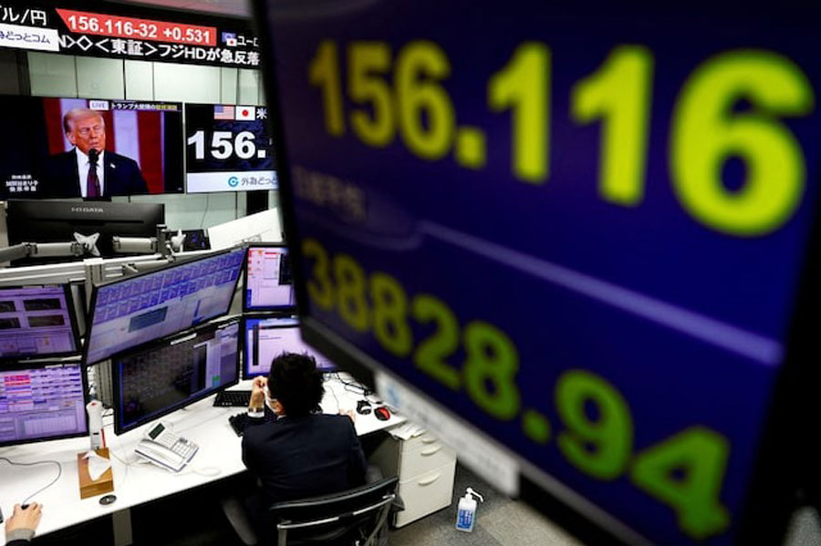 An employee of the foreign exchange trading company Gaitame.com works near a screen broadcasting US President Donald Trump's inauguration speech while another screen displays Japan's Nikkei share average and the current Japanese Yen exchange rate against the US dollar, at their dealing room in Tokyo, Japan January 21, 2025.