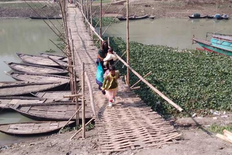 In absence of a permanent concrete bridge, locals crossing the Karatoya River by using a makeshift bamboo bridge at the Baharampur-Mirzapur point in Chatmohar upazila of Pabna district
