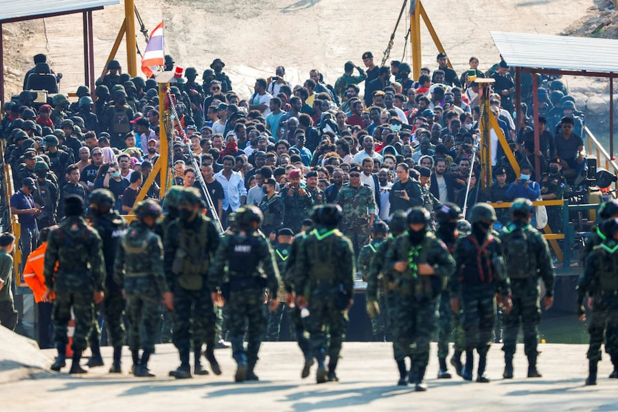 Multinational victims of scam centers, who were tricked or trafficked into working in Myanmar, stand on a vessel floating towards the Thai side of border via Moei River in Phop Phra District, Tak province, Thailand February 12, 2025.