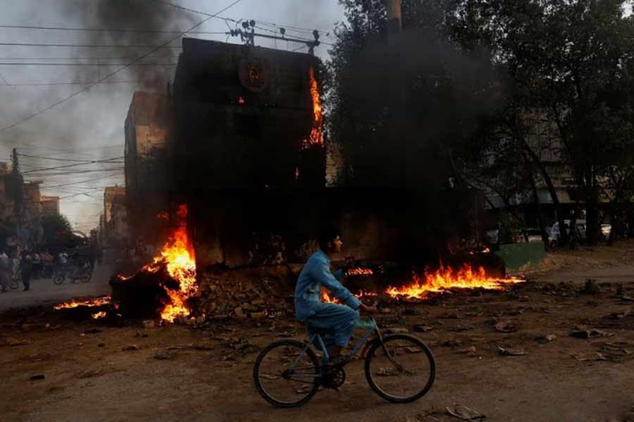 A boy riding past a paramilitary check post, which was set afire by the supporters of Pakistan's former Prime Minister Imran Khan, during a protest against his arrest in Karachi on Tuesday –Reuters photo