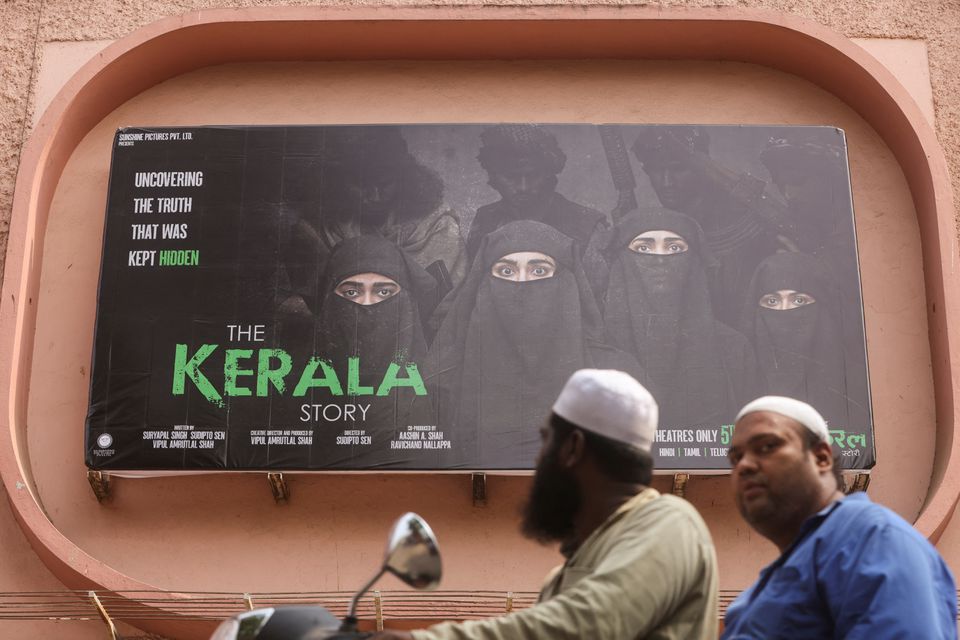 People ride past a poster of a Hindi movie titled "The Kerala Story", outside a cinema in Mumbai, India May 9, 2023. REUTERS/Francis Mascarenhas
