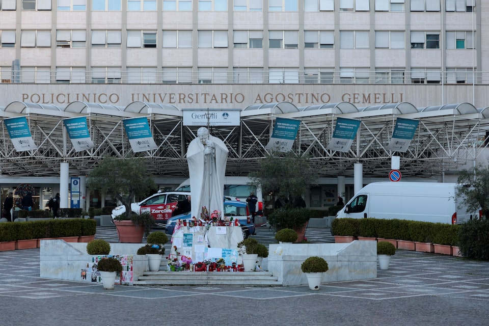 Messages, candles and flowers are placed near the statue of late Pope John Paul II outside Gemelli Hospital where Pope Francis is admitted for treatment, in Rome, Italy, March 5, 2025. REUTERS/Remo Casilli