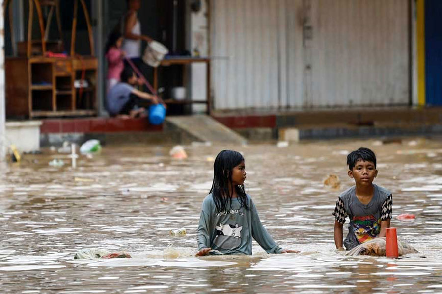 Children wade through water in a flooded residential area following heavy rains in Bekasi, on the outskirts of Jakarta, Indonesia, Mar 4, 2025.