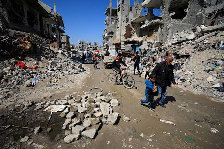 Palestinians pass by the rubble of destroyed houses, in Gaza City, March 11, 2025.