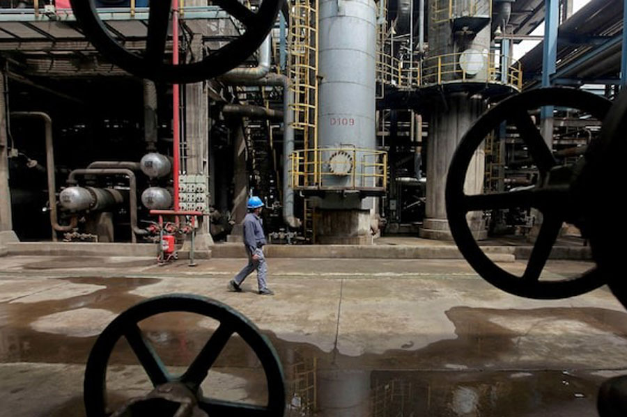 A worker walks past oil pipes at a refinery in Wuhan, Hubei province March 23, 2012.