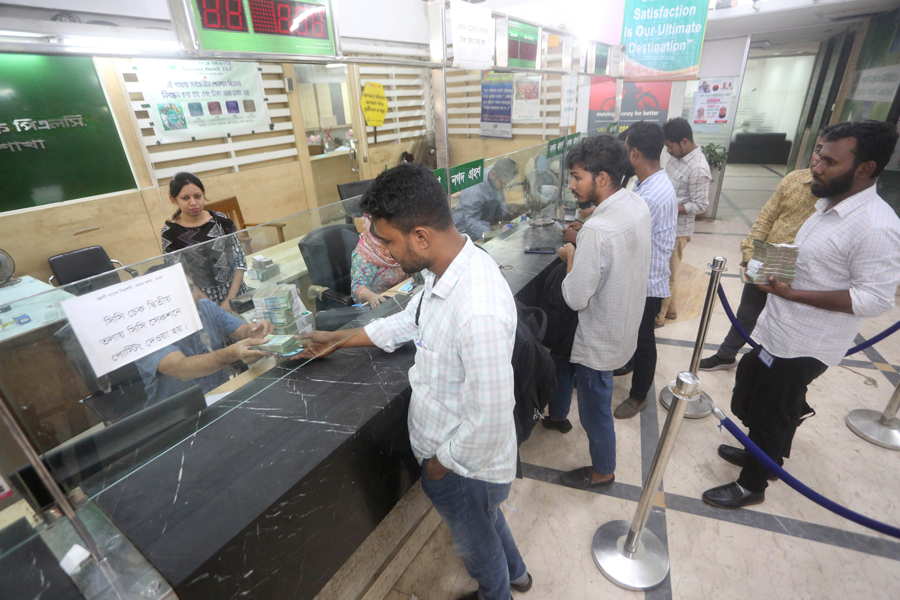Customers depositing cash at a bank branch in Dhaka.
