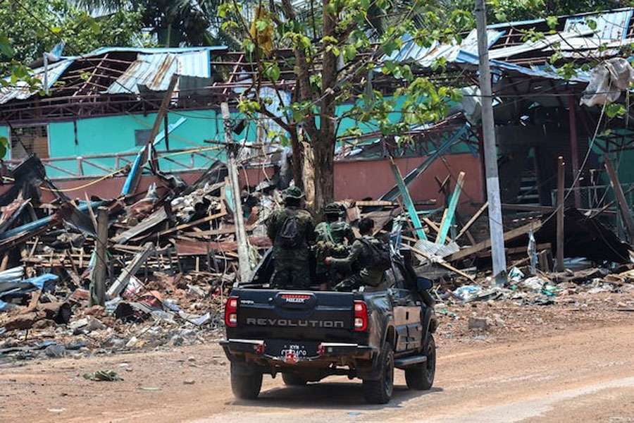 Soldiers from the Karen National Liberation Army (KNLA) patrol on a vehicle, next to an area destroyed by Myanmar's airstrike in Myawaddy, the Thailand-Myanmar border town under the control of a coalition of rebel forces led by the Karen National Union, in Myanmar, April 15, 2024.