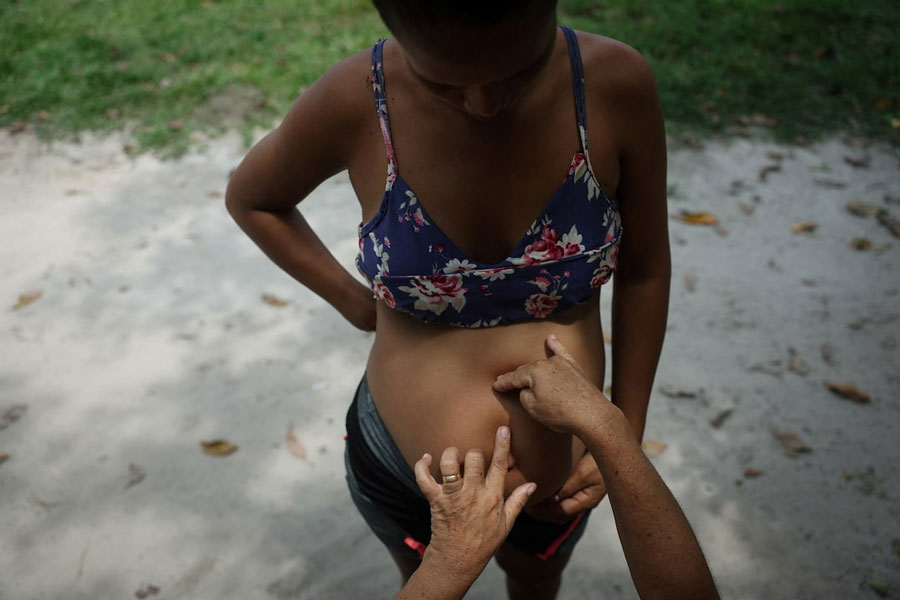Midwife Tabita dos Santos Moraes, 51, touches the belly of Mayleane Melo, 22, to monitor the baby’s position, at the Deus e Pai community in Tefe, Amazonas state, Brazil, October 24, 2024.