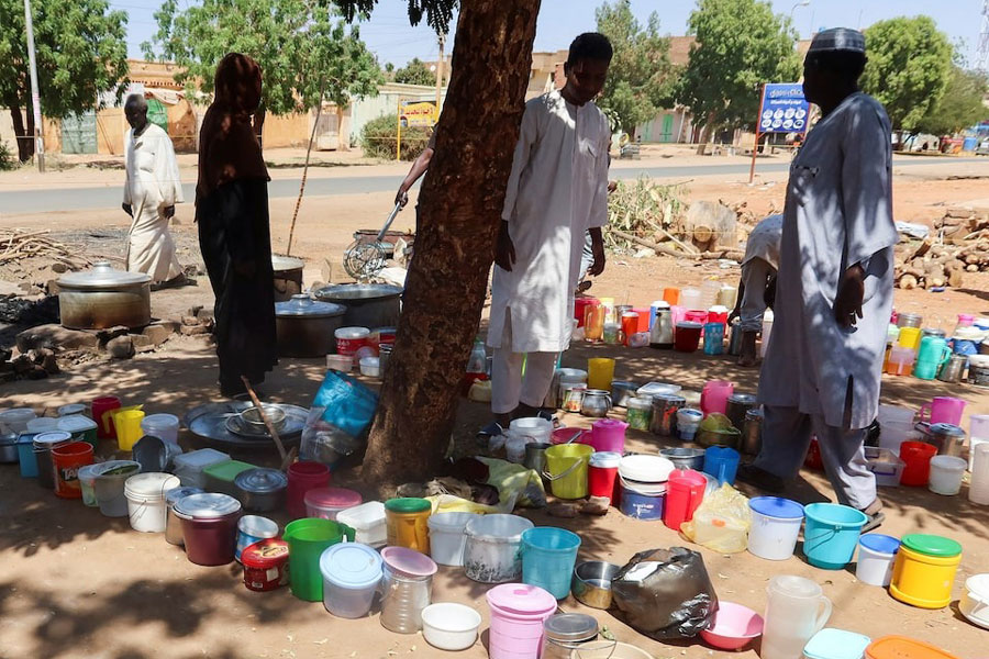 Sudanese men stand next to empty containers in front of "Takaya" the charity restaurant and a community kitchen, that helps the needy Sudanese in Omdurman areas recently controlled by army during the conflict and war, during the holy month of Ramadan in the state of Khartoum, Sudan March 14, 2025.