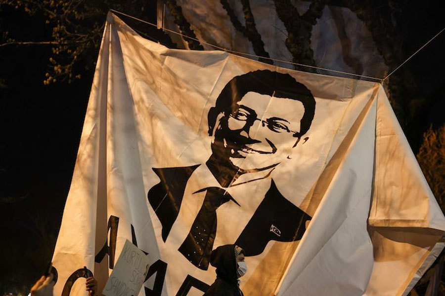 A person walks past a banner with an image of Istanbul Mayor Ekrem Imamoglu, as people take part in a protest against the detention of Imamoglu, in Istanbul, Turkey, March 20, 2025.