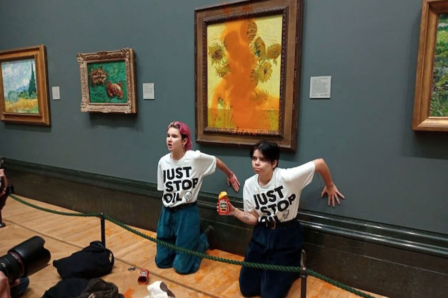 Activists of "Just Stop Oil" glue their hands to the wall after throwing soup at a van Gogh's painting "Sunflowers" at the National Gallery in London, Britain October 14, 2022.