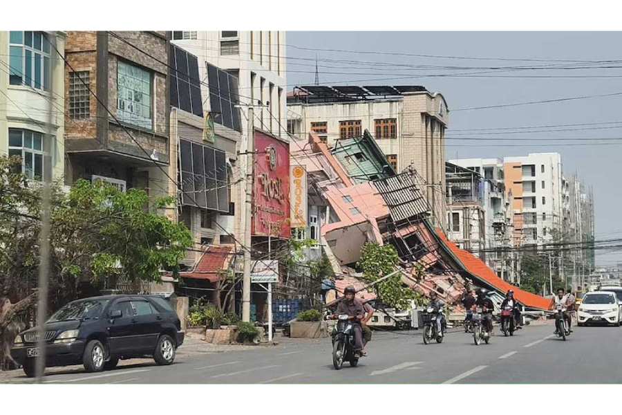 People ride motorcycles past a damaged building after a strong earthquake struck central Myanmar, in Mandalay, Myanmar, Mar 28, 2025.