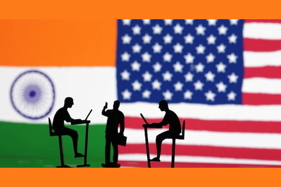 The Indian flag, the US flag and people miniatures, some with laptops, are seen in this illustration taken March 10, 2024.