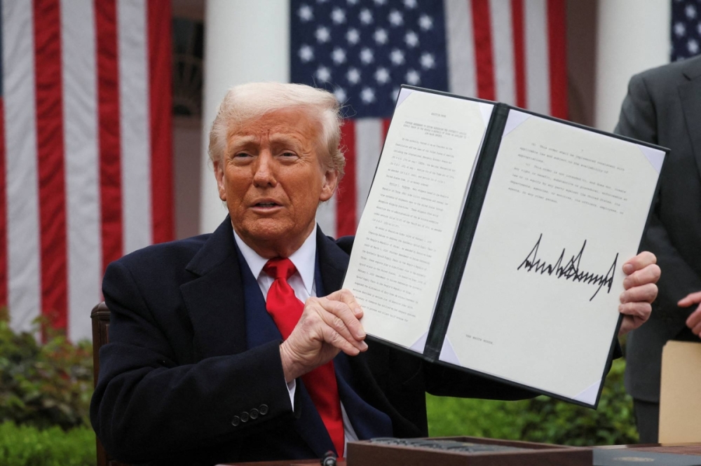 Trump holds up a signed executive order on tariffs, in the Rose Garden at the White House in Washington on Wednesday. | REUTERS
