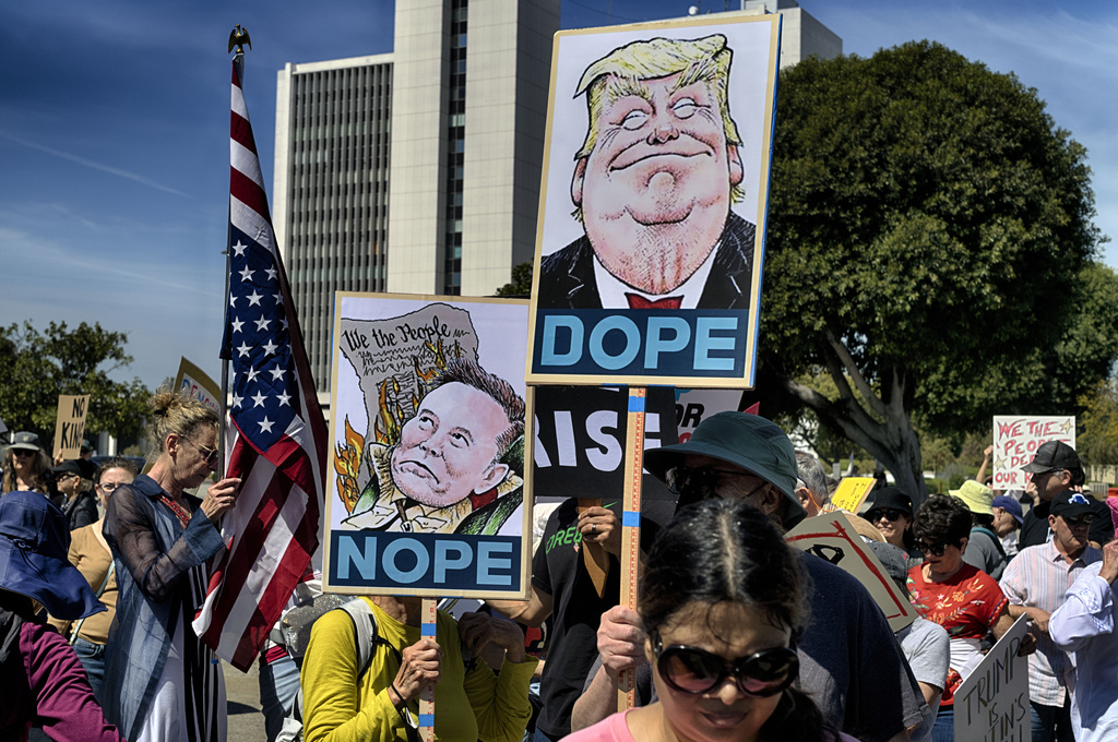Protesters carry signs and chant slogans in protest to the policies of President Donald Trump and Elon Musk across from the Federal Building in the Westwood section of Los Angeles, Saturday, March 22, 2025. (AP Photo/Richard Vogel, File)