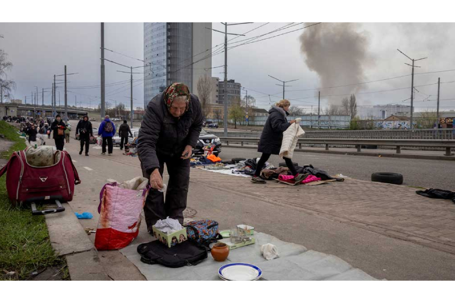 Vendors put their wares on display at a flea market as smoke rises from a nearby site of a Russian missile strike, amid Russia’s attack on Ukraine, in Kyiv, Ukraine, Apr 6, 2025.