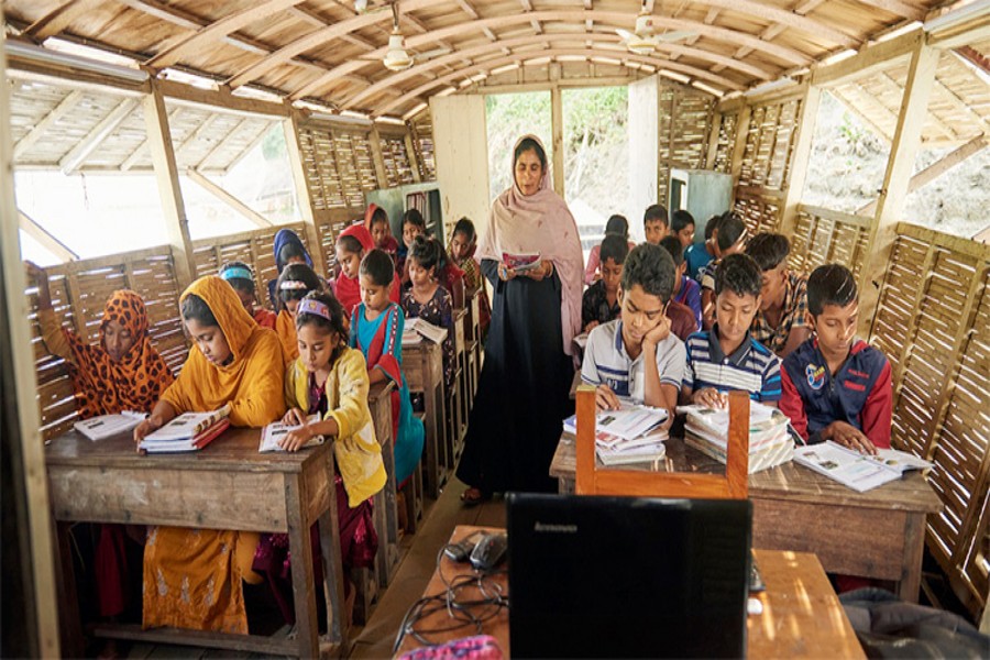 The photo shows a teacher teaching students at a floating school aboard a boat in Chalanbil area in Chatmohar Upazila of Pabna district
