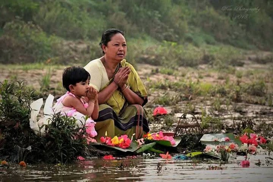 Indigenous woman and her daughter immerse flowers in a river of Rangamati district on Saturday