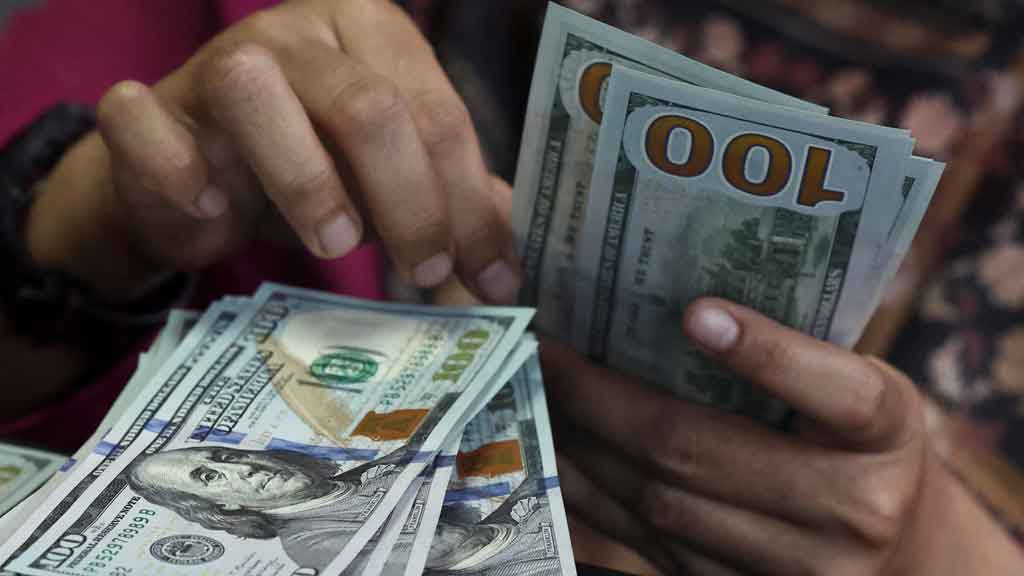A teller counts US dollar bank notes at a money changer in Jakarta, Indonesia, Apr 9, 2025. Picture taken through glass. REUTERS/Willy Kurniawan