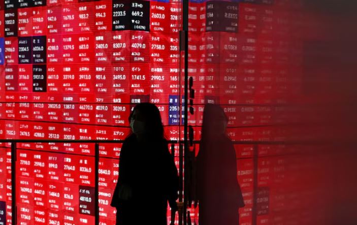 A woman walks in front of a stock quotation board inside a builidng in Tokyo, Japan April 25, 2025. REUTERS/Issei Kato/File Photo