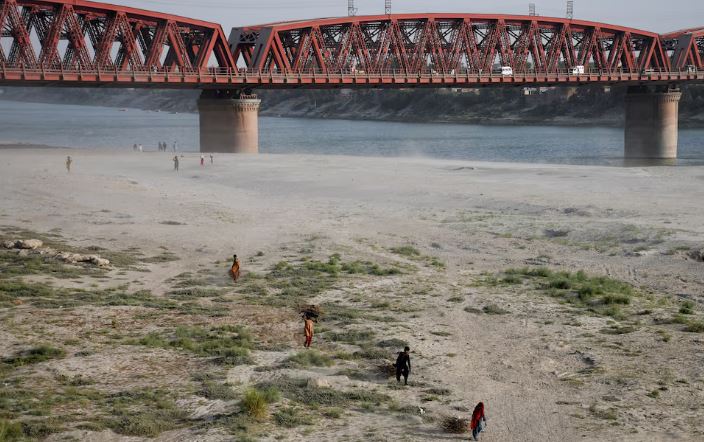 People walk on the dry riverbed of the Indus River in Hyderabad, Pakistan April 24, 2025. REUTERS/Yasir Rajput/File Photo