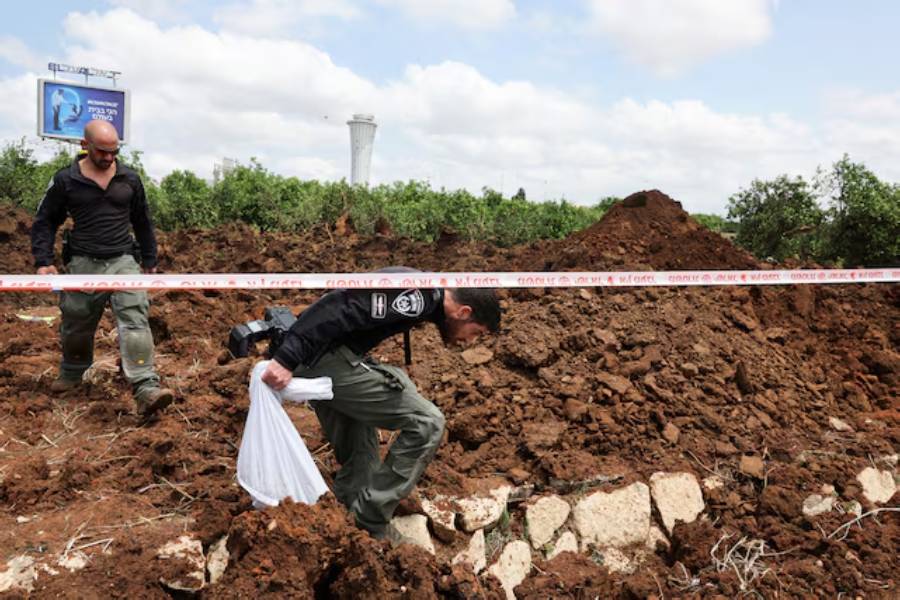 Israeli police officers investigate a crater at the site of a missile attack, launched from Yemen, near Ben Gurion Airport, in Tel Aviv, Israel May 4, 2025.
