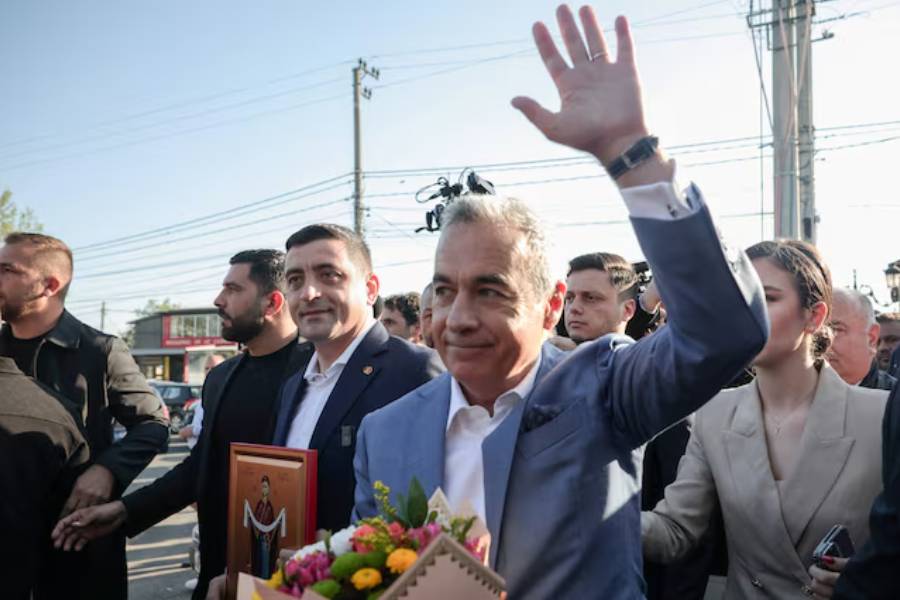 Calin Georgescu waves next to presidential candidate George Simion after casting their votes in country's first round of the presidential election, in Mogosoaia, Romania, May 4, 2025.