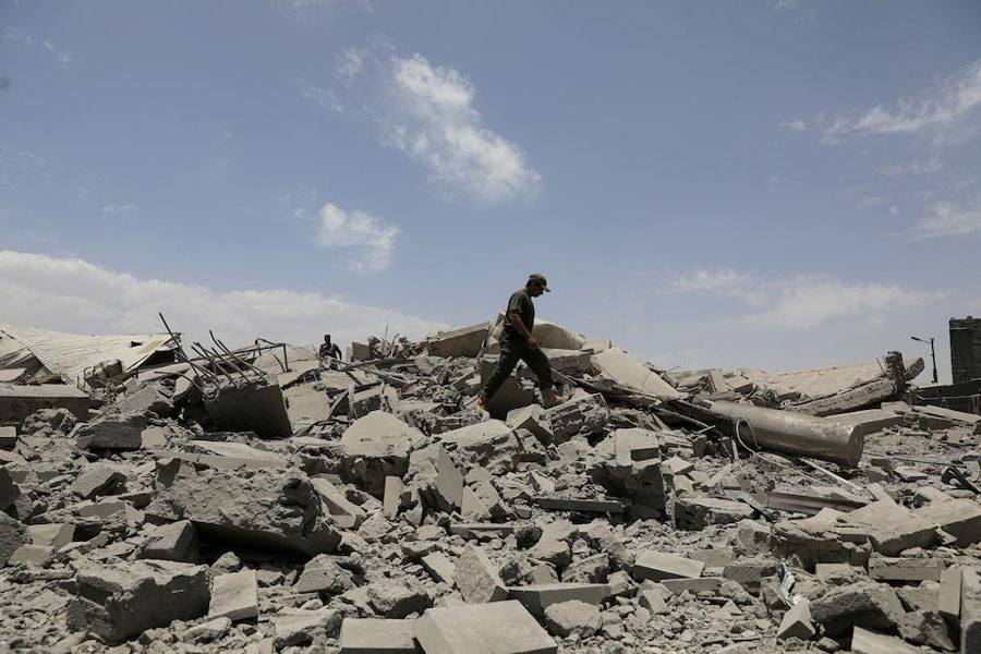 A police trooper walks on the rubble of a building destroyed by US air strikes in Sanaa, Yemen April 27, 2025.