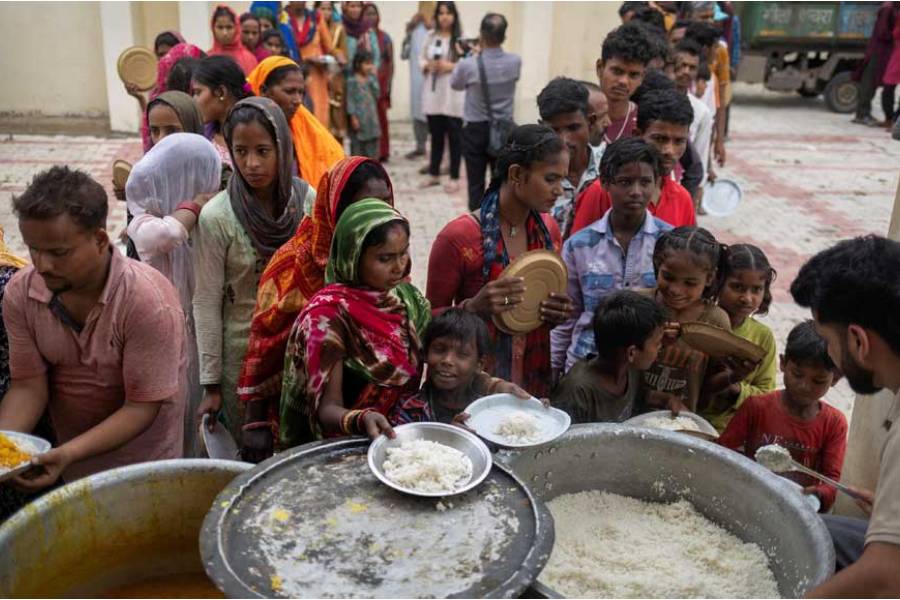 People who were evacuated from an area near the Line of Control (LoC) between India and Pakistan following cross-border shelling stand in queues to receive food at a college that was turned into a temporary shelter on the outskirts of Jammu, May 8, 2025.