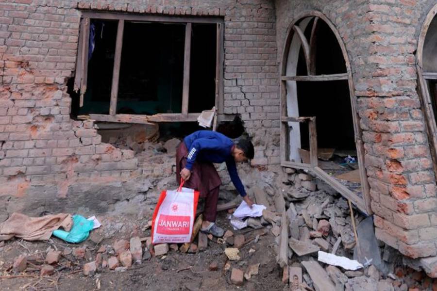 A boy collects papers from the debris of a residential house damaged by a cross-border shelling in Gingal village near the Line of Control (LoC) between India and Pakistan, in Indian Kashmir's Baramulla district, May 9, 2025.