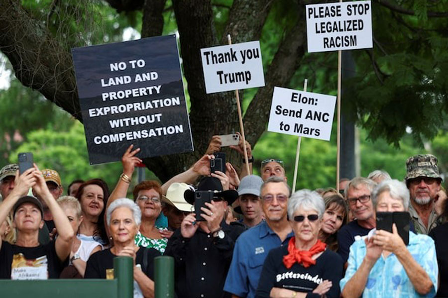 Demonstrators hold placards in support of US President Donald Trump's stance against what he calls racist laws, land expropriation, and farm attacks, outside the American Embassy in Pretoria, South Africa, February 15, 2025.