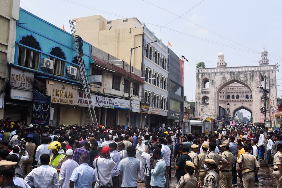 Firefighters, police and crowds stand outside of the building (blue-coloured) that caught fire in Hyderabad, India, May 18, 2025. REUTERS/Stringer