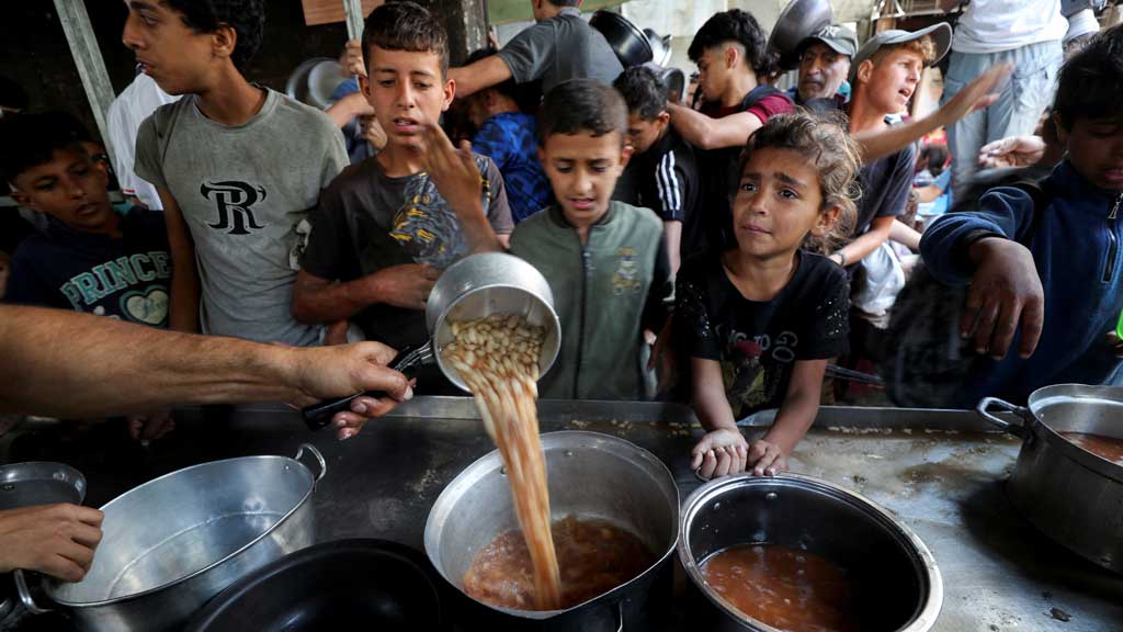 Palestinians wait to receive food cooked by a charity kitchen, in Gaza City, May 21, 2025. REUTERS