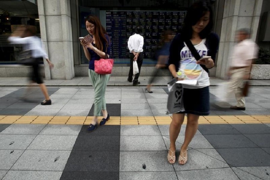 A pedestrian looks at an electronic board showing the various stock prices outside a brokerage in Tokyo, Japan, September 4, 2015. Reuters/File Photo