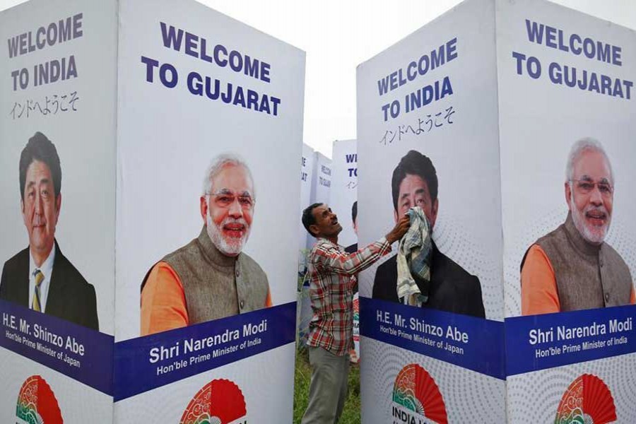 A worker cleans a hoarding featuring Prime Minister Narendra Modi and his Japanese counterpart Shinzo Abe ahead of Abe's visit, in Ahmedabad on September 10. - Reuters photo