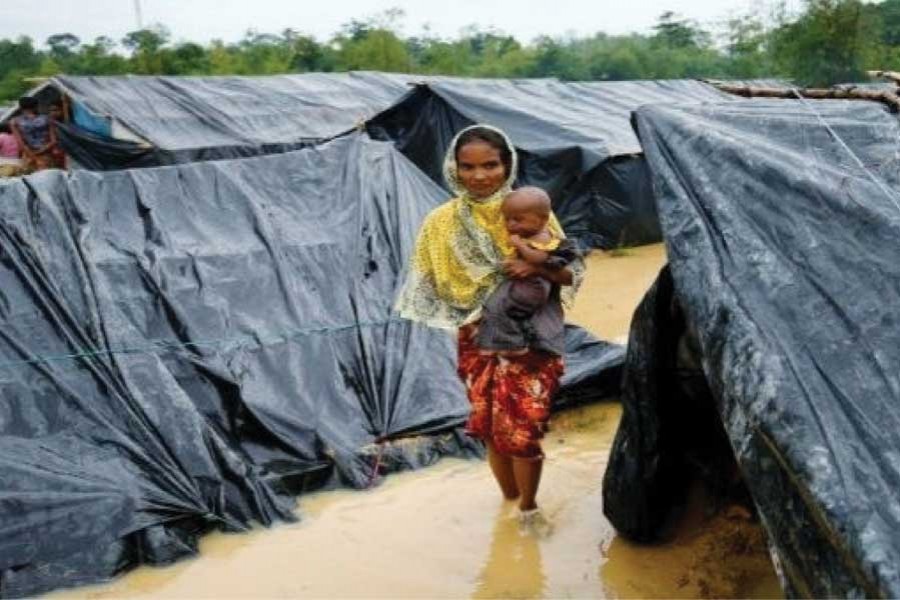 A Rohingya refugee woman and her child walk in floodwaters near makeshift shelters after heavy rains in Cox's Bazar in the second week of September, 2017. —Photo: Reuters