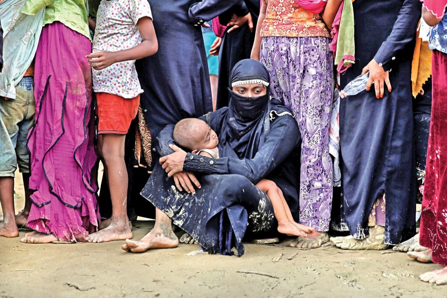 A group of Rohingya refugees wait to receive aid in Cox's Bazar on Wednesday. — Reuters