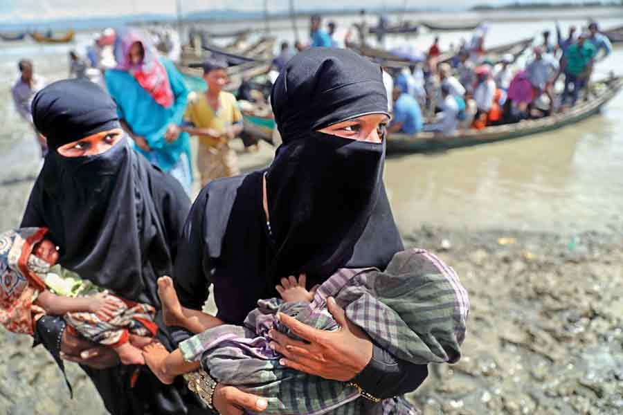 Two Rohingya refugees, who just arrived from Myanmar with their newborn babies, walk towards a relief centre in Teknaf under Cox's Bazar on Tuesday. — Reuters